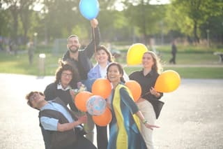 SAIN Amsterdam graduates celebrating outdoors with balloons and flowers