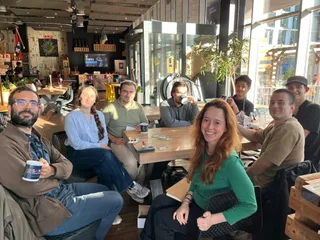 A discussion group around a café table, some holding SAIN Amsterdam mugs